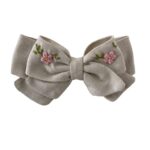 Moño de lino beige bordado a mano en tonos rosa pastel,